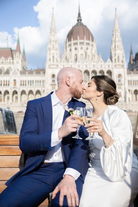 brida and groom kiss with champagne on a Danube cruise during their elopement in Budapest
